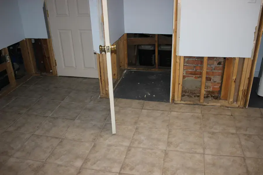 Flood-cut drywall removed along the lower walls of a tiled room during drying